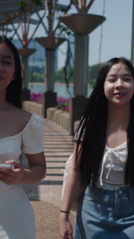 Two friends are walking and looking at their smartphones, sharing and enjoying social media content