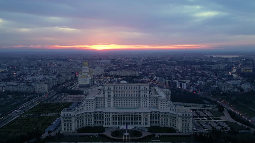 Aerial drone footage of the house of the people in Bucharest. High angle golden hour shot of the  Parliament building in the capital or Romania. Massive governmental structure seen from the air.
