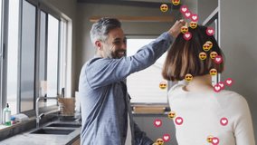 Lifestyle couple with man lifting partner hand causing twirl in kitchen with floating heart emojis. Romance, intimacy, affection, celebration, joy, connection, movement - Powered by Shutterstock - Get 15% off with code: PIKWIZARD15