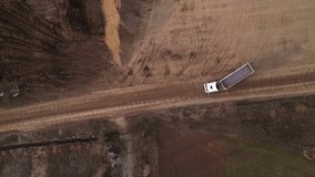 Aerial high angle footage of end dump truck unloading dirt and gravel at a dump site during the construction of a highway.  Top down drone view of  dumping payload after hauling from industrial site. - Powered by Shutterstock - Get 15% off with code: PIKWIZARD15