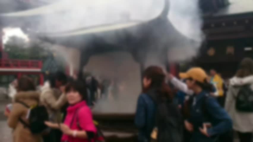 Blurred figures burning incense at serene temple, spiritual atmosphere, peaceful ambiance
