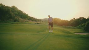 Slow motion walk-up shot of a male golfer putting from the fringe with golden hour sun flares in the frame. A warm, cinematic moment capturing the quiet focus and beauty of evening golf. - Powered by Shutterstock - Get 15% off with code: PIKWIZARD15