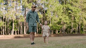 Asian adult father and young daughter holding hands walking together on grassy field in forest national park enjoying quality time and connection during peaceful family vacation day in nature - Powered by Shutterstock - Get 15% off with code: PIKWIZARD15