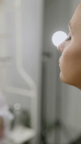 Makeup, beauty salon concept. Female makeup artist spraying spray on model face. Close-up vertical video