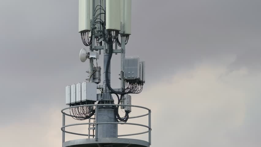 Telecommunications Tower upper antenna part with cloudy sky in the background