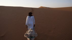 Camel ride at sunset through the golden dunes of Erg Chebbi in Morocco, led by a Berber guide in traditional attire, with soft light and footprints marking the path in the Sahara Desert - Powered by Shutterstock - Get 15% off with code: PIKWIZARD15