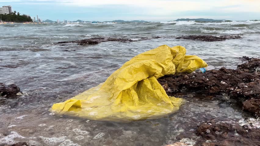 yellow plastic bag on rocky ocean shore. ecological problem of mankind. environmental pollution