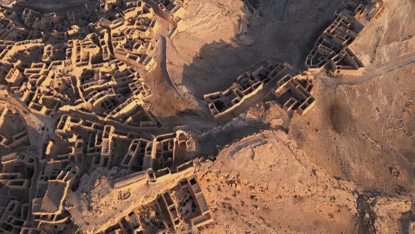 An ancient city made up of stone structures with a sky background. Some of the structures have a roof. The ground is rocky and uneven, with a dusty atmosphere. Location: Tunisia, Gabes , Zraoua.