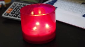 Red glass candle burning on black office desk—great for calm workspace, ambient design, relaxation, or holiday-themed projects. - Powered by Shutterstock - Get 15% off with code: PIKWIZARD15