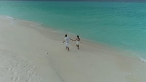 Aerial view of a couple walking on a private Caribbean beach in Los Roques, Venezuela, drawing a heart in the white sand by the turquoise sea. - Powered by Shutterstock - Get 15% off with code: PIKWIZARD15