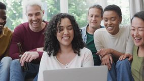 Curly-haired woman holding laptop initiating emoji cascade for tech demo with friends reacting. Collaboration, socializing, entertainment, digital interaction, casual, vibrant, diverse - Powered by Shutterstock - Get 15% off with code: PIKWIZARD15