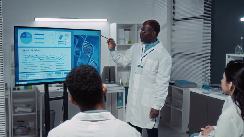 Medium full shot of group of multiethnic bioengineering university students attending seminar on DNA and genetics, listening to black male professor giving lecture with presentation, asking questions