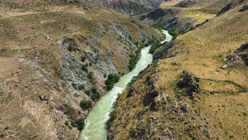 Aerial view of a winding river carves its way through a rugged canyon, where the water