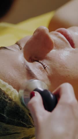Cosmetology, facial skin care procedures. close-up. phonophoresis procedure for facial skin. beautician leads special maniple along massage lines on face. anti-aging cosmetics.