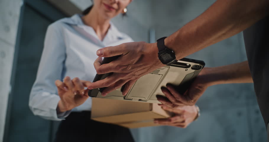 Close Up of Postman Delivering Parcel Box to Addressee in Modern Office, Getting Client's Signature on Digital Tablet. Businesswoman Taking Package with Online Shopping Order. Delivery, Postal Service