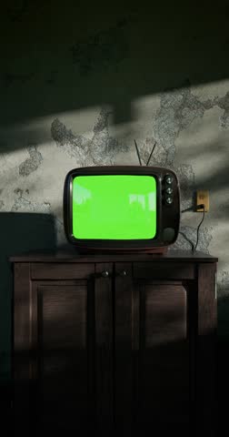 Retro TV turns on with noise in a dim room. Textured walls and trees cast shadows on the cabinet. Chroma key template. The last 120 frames loop swaying tree shadows. Vertical CGI clip