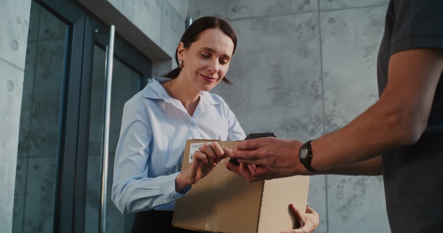 Postman Coming to Modern Office Building, Delivering Parcel Box for Recipient. Businesswoman Receiving Her Package with Online Shopping Order, Signing POD on Smartphone. Delivery or Postal Service.