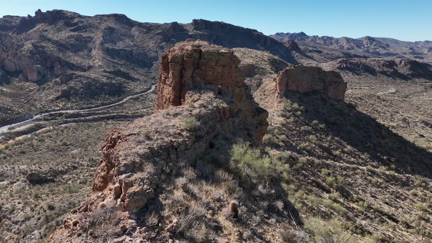 Aerial view of the rugged Superstition Mountains shows dramatic rock formations and arid landscape under a clear blue sky, Apache Junction, Arizona, United States.