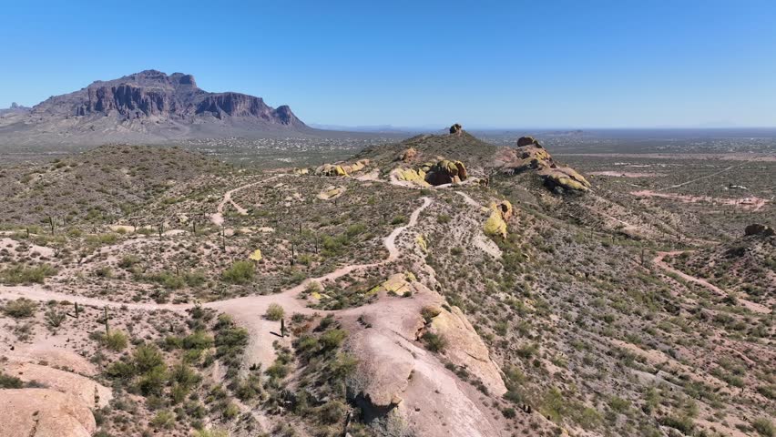 Aerial view of the rugged desert landscape with winding trails and the iconic Superstition Mountains in the background, Apache Junction, Arizona, United States.