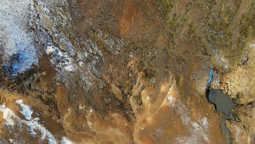 Aerial view of a geothermal area with steam rising from the light blue water, contrasting with the surrounding brown and white terrain, Grindavíkurbaer, Iceland.