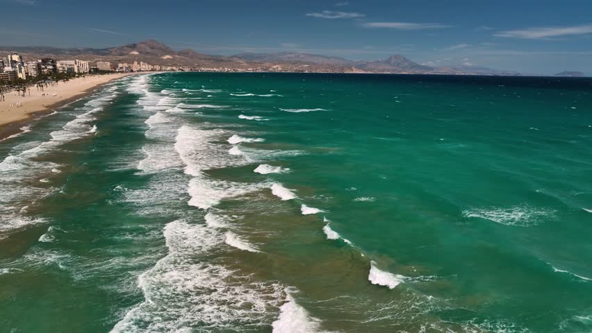 Aerial view of the turquoise ocean meeting the sandy beach of Playa San Juan, with buildings lining the coast, Playa San Juan, Canarias, Spain.