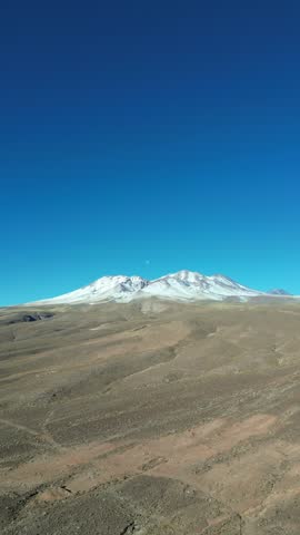 Aerial View of A rugged landscape in Chile unfolds, contrasting snow-capped mountain peaks against the arid desert, San Pedro de Atacama, Antofagasta, Chile.
