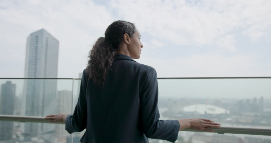 Businesswoman Walking on Office Rooftop in City, Looking out over City Skyline