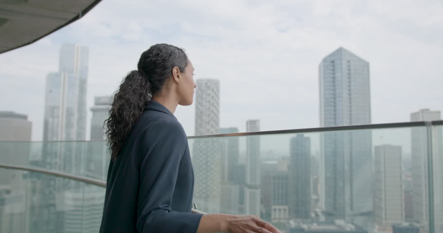 Businesswoman Walking on Office Rooftop in City, Looking out over City Skyline