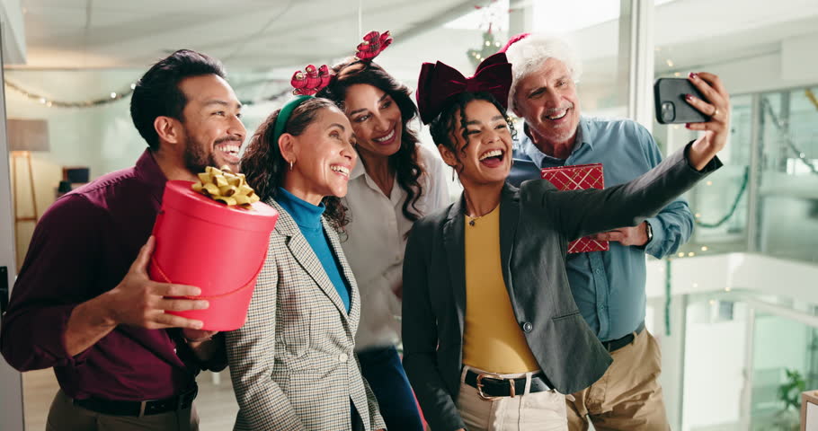 Christmas, selfie and group of business people laugh at festive celebration with gifts. Xmas, team and photo of friends in office for holiday spirit, peace sign or wave for social media post at party