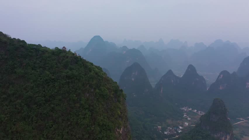Aerial view of a dramatic mountain range shrouded in mist, offering a serene yet imposing landscape of natural beauty, Xianyang, Shaanxi, China.