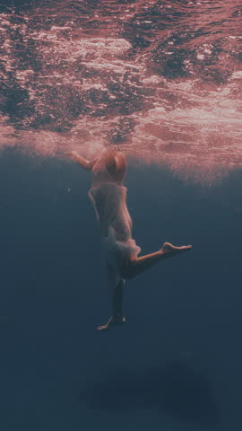 Beautiful young woman swimming underwater with dolphins in pristine blue ocean water, amazing snorkeling adventure. Armature freediver girl diving in red sea with bottlenose dolphins. Travel concept