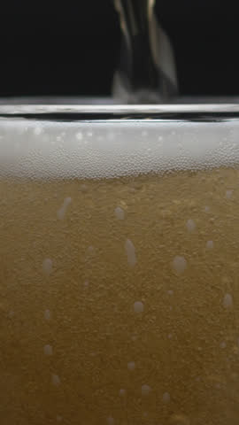 Beer pouring and splashing in super slow motion with visible foam and bubbles. Close-up macro shot capturing refreshing texture and movement, perfect for beverage commercials or drink promos.