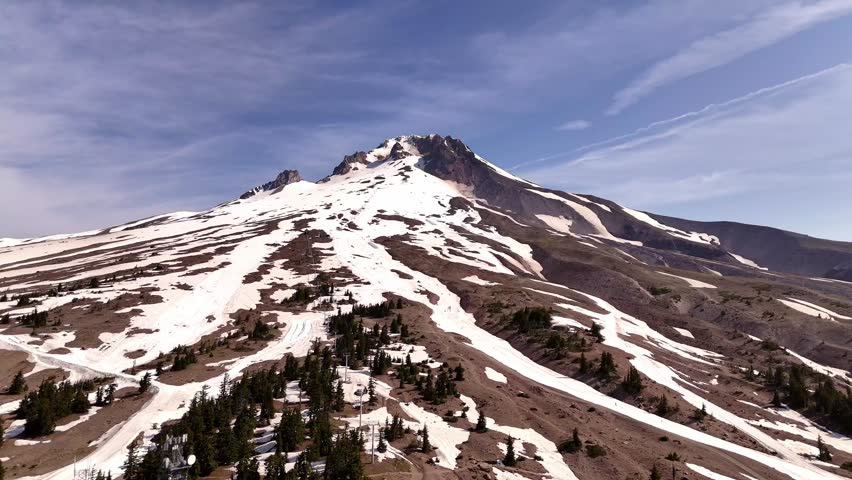 Aerial view of a majestic mountain partially covered in snow, a stunning contrast of white against the brown earth, Government Camp, Oregon, United States.