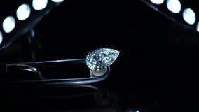 A gleaming pear-shaped diamond meticulously held on a specialized gem holder under precise lighting, highlighting its exceptional brilliance and unique cut. - Powered by Shutterstock - Get 15% off with code: PIKWIZARD15