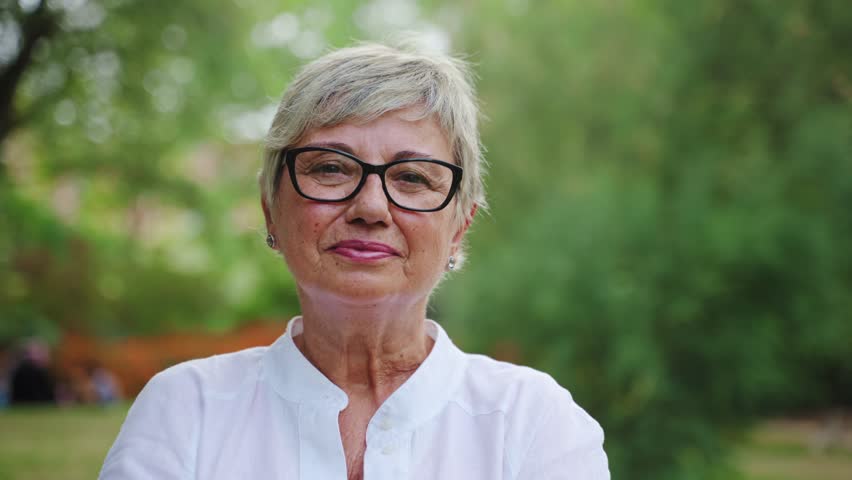 Portrait of lovely senior woman smiling in the park. Happy grandma