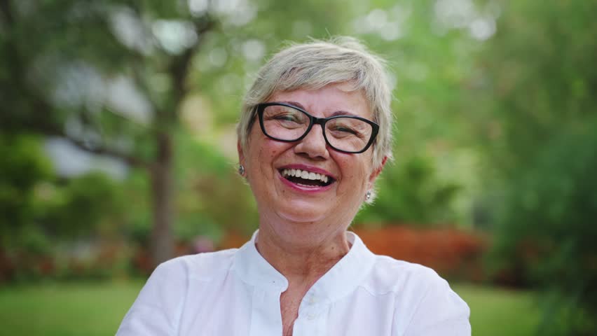 Portrait of lovely senior woman smiling in the park. Happy grandma