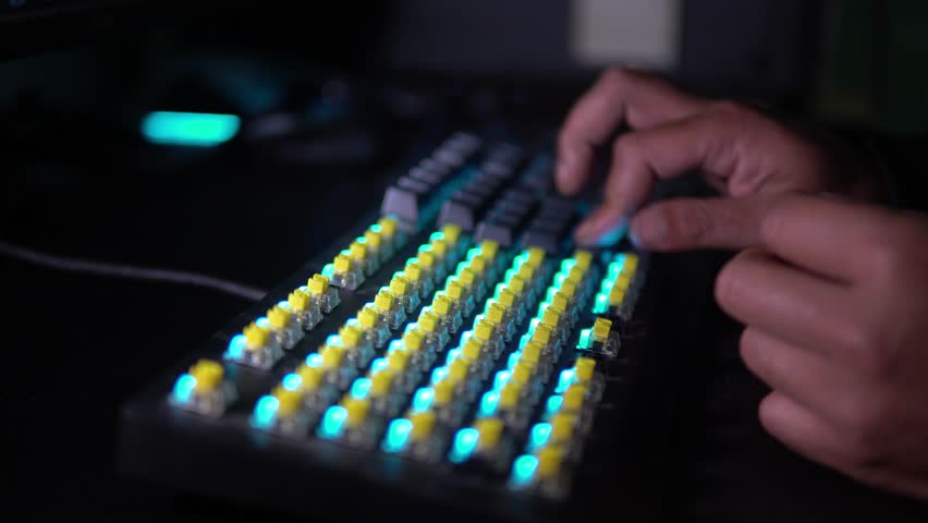 Close-up of hands installing keycaps on an RGB mechanical keyboard. Yellow switches and blue backlight create a modern tech aesthetic. Perfect for tech builds or gaming content.