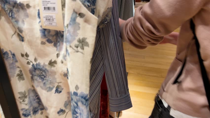 A girl looking at some models of clothes to choose what she likes. Upmarket French department store Galeries Lafayette Haussmann, Paris, France.