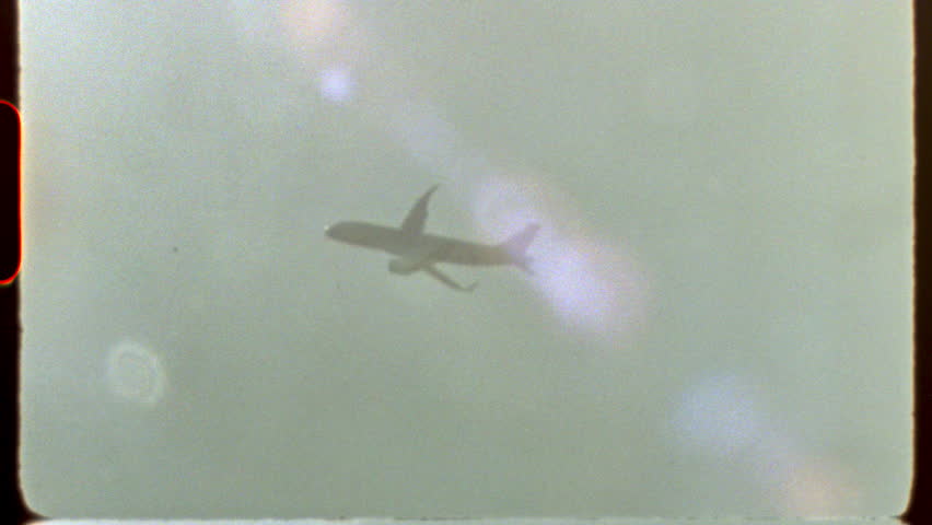 Filmed on super 8 film - airplane traversing cloudy skies, capturing nostalgic Super 8 film aesthetic with atmospheric lens flare and evocative light leaks in classic documentary style