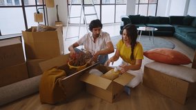 Couple sharing hearty laughter while unpacking cardboard boxes in bright living room, surrounded by furniture during moving day, embodying teamwork and joyful new beginnings - Powered by Shutterstock - Get 15% off with code: PIKWIZARD15