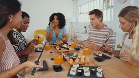 Group of friends enjoys a shared sushi meal, laughing and feeding each other in a cozy home setting, capturing moments of fun and friendship - Powered by Shutterstock - Get 15% off with code: PIKWIZARD15