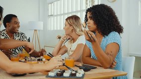 Group of friends enjoys a shared sushi meal, laughing and feeding each other in a cozy home setting, capturing moments of fun and friendship - Powered by Shutterstock - Get 15% off with code: PIKWIZARD15
