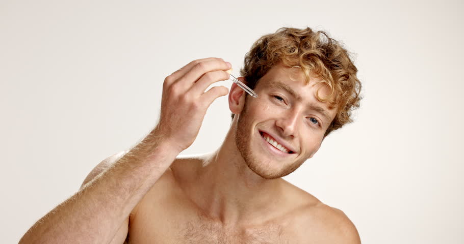 Serum, skincare and face of man in studio for vitamin c, beauty and facial treatment. Essential oil, cosmetics and self care with person and dropper on white background for dermatology and glow