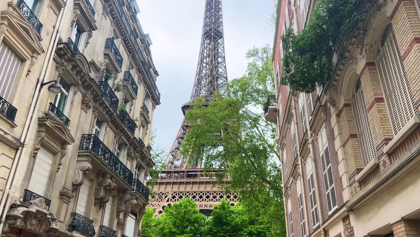 View of beautiful historic buildings and the Eiffel Tower from lively Rue Buenos-Ayres street, 8th arrondissement, Paris, France.
