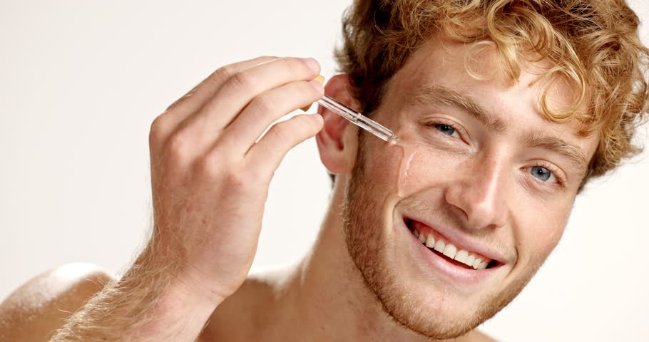 Serum, beauty and face of man in studio for vitamin c, skincare and facial treatment. Essential oil, cosmetics and self care with person and dropper on white background for dermatology and glow