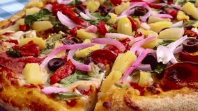 Close up macro dynamic view holding a slice of colorful vibrant pizza with red, green, yellow peppers, mushrooms, vegetables, pineapple, onions, and pepperoni toppings on a picnic table background - Powered by Shutterstock - Get 15% off with code: PIKWIZARD15