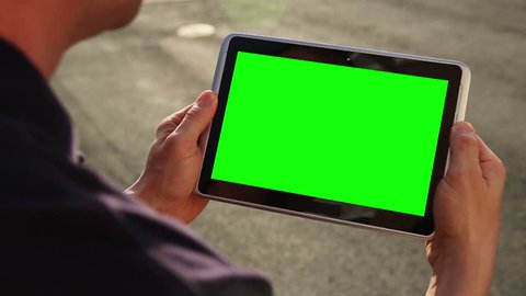 A man holds a blank tablet PC with a green screen for your own custom content. Arkistovideo