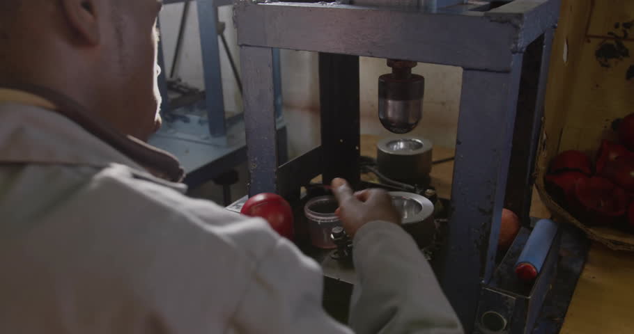 Technician gripping lever in factory crushing apple under press with AR overlays updating metrics. Mechanical, industrial, futuristic, technology, manufacturing, precision, innovation