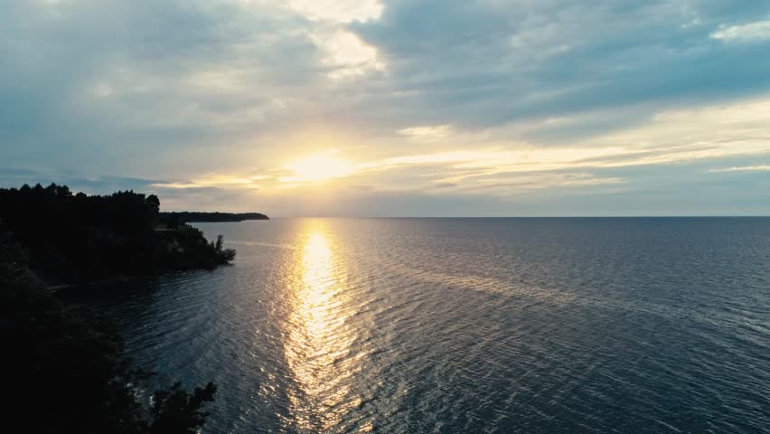 Drone overflight of Lake Ontario from the New York shore looking west towards a sunset in mid summer