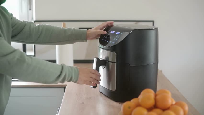 Close up footage of an air fryer being opened, closed, and standard temperature or time settings being entered on the digital display. Perfect for cooking, appliance, and modern kitchen content.